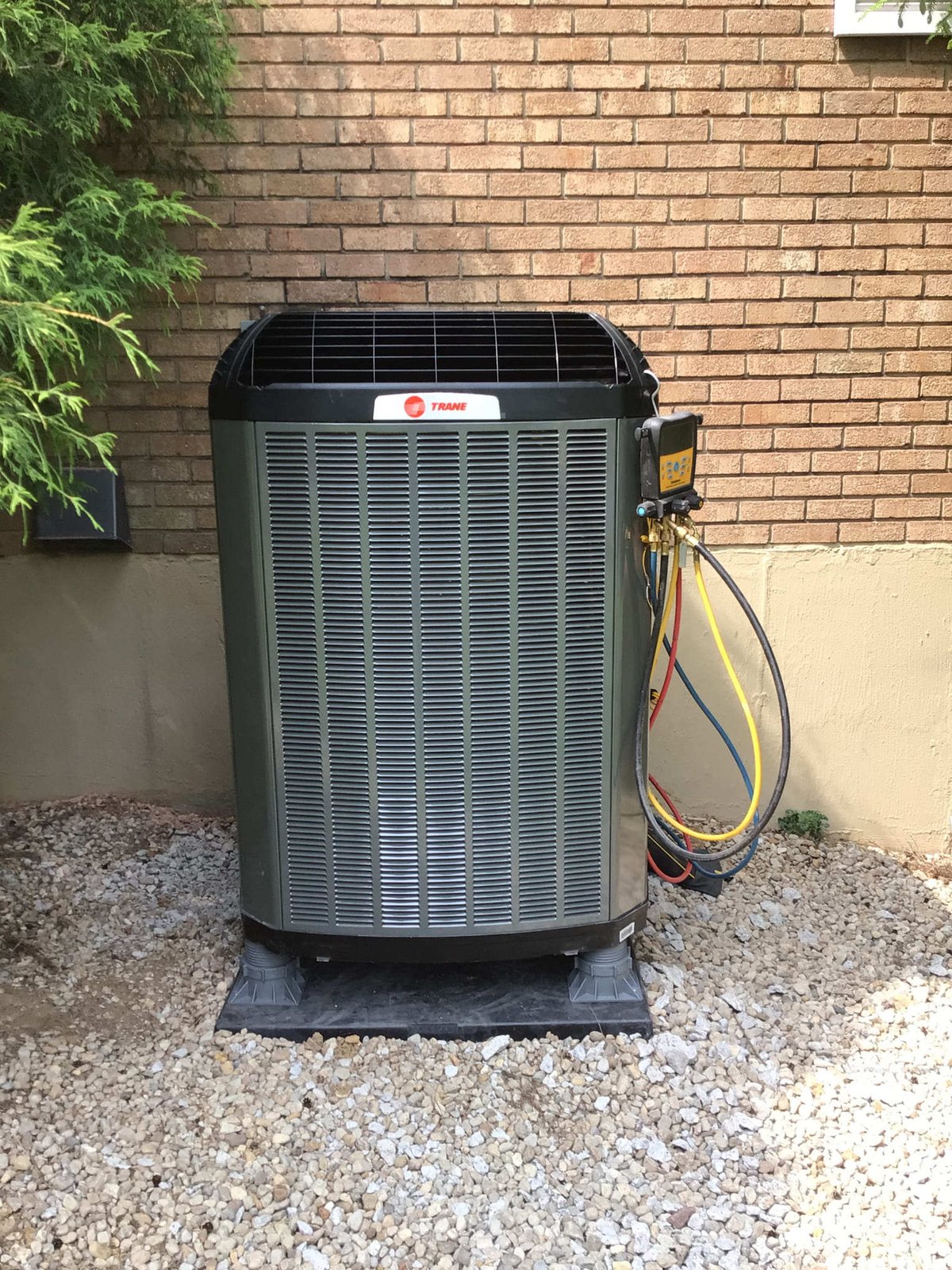 Trane residential air conditioning unit being serviced with refrigerant gauges connected